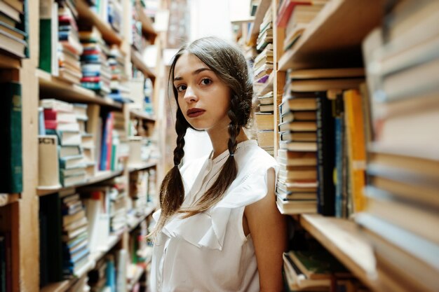 Garota com tranças na blusa branca na antiga biblioteca