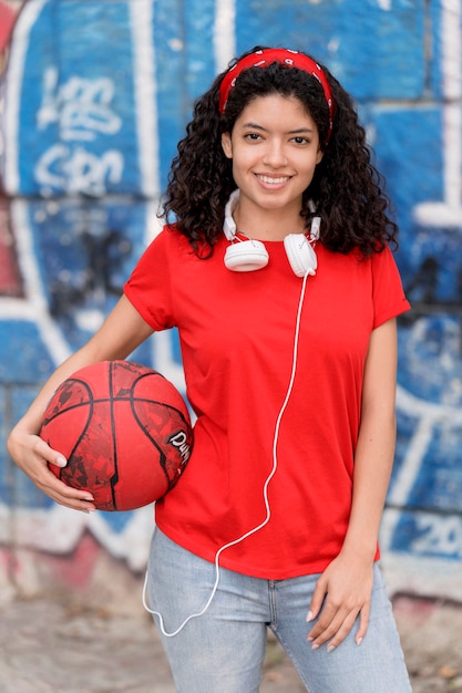 Foto grátis garota com vista frontal segurando uma bola de basquete