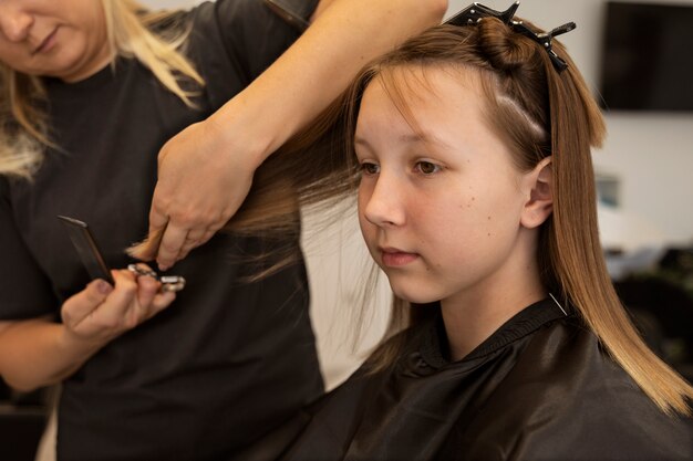 Garota cortando o cabelo na vista lateral do salão