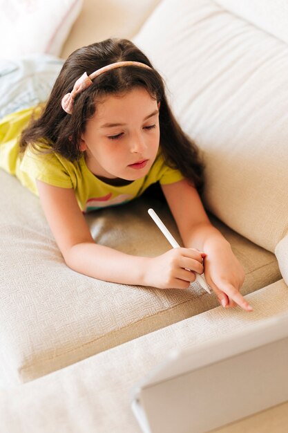 Garota de alto ângulo apontando para seu tablet