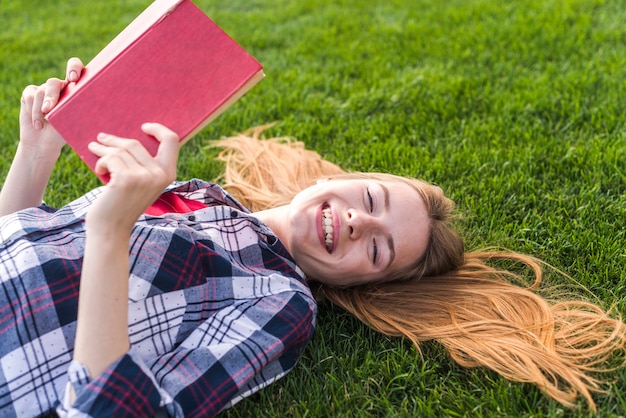 Garota de alto ângulo, lendo um livro na grama