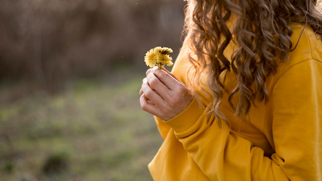 Garota de camisa amarela, segurando uma flor vista média