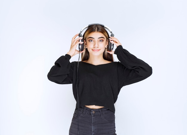 Garota de camisa preta usando fones de ouvido e ouvindo música. Foto de alta qualidade