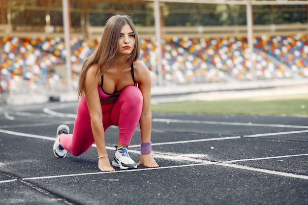 Garota de esportes em um uniforme rosa é executado no estádio