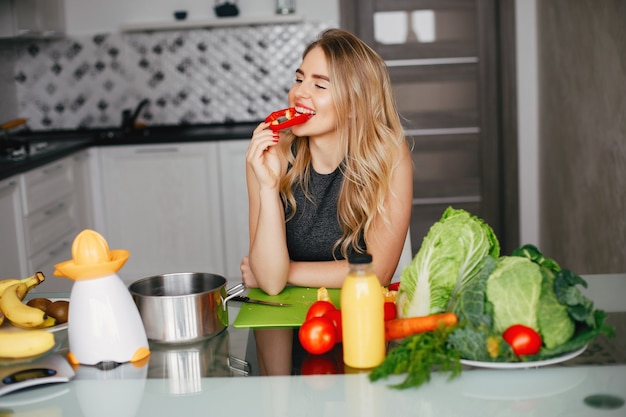 Garota de esportes em uma cozinha com legumes