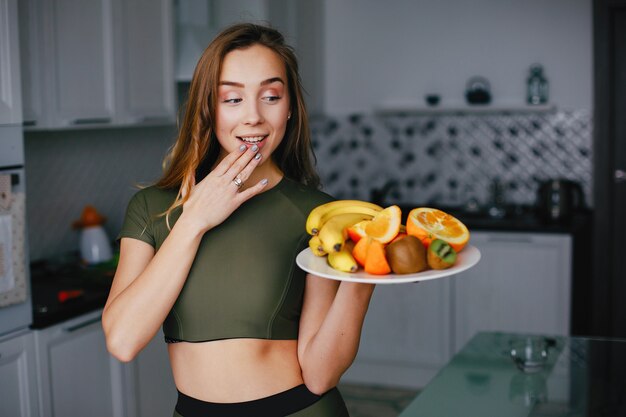 Garota de esportes em uma cozinha com legumes