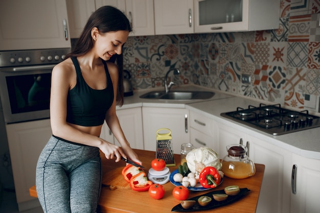 Garota de esportes em uma cozinha com legumes