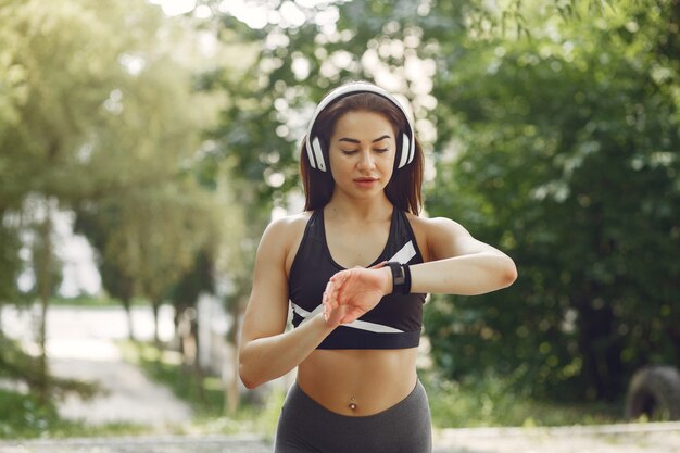 Garota de esportes treinando com fones de ouvido em um parque de verão
