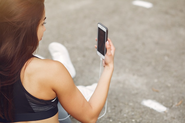 Garota de esportes treinando com telefone e fones de ouvido