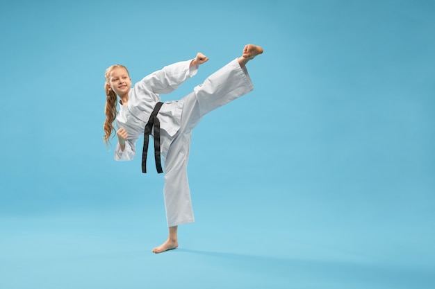 Garota de karatê no quimono branco praticando artes marciais.