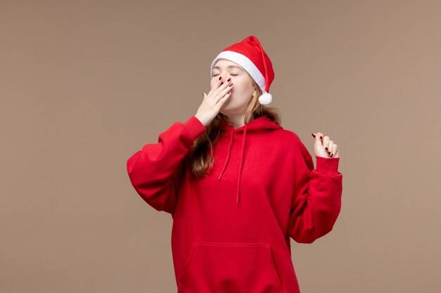 Garota de natal bocejando em um fundo marrom mulher férias natal