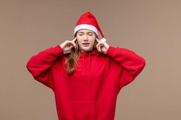 Garota de natal de frente fechando os ouvidos no fundo marrom modelo férias natal