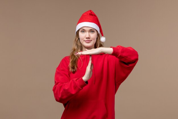 Garota de natal frontal posando com um sorriso no fundo marrom, férias natalinas, emoção