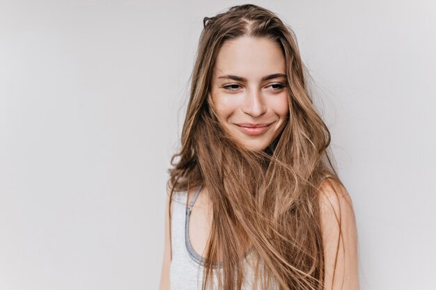 Garota de olhos escuros entusiasmada isolada com um sorriso encantador. retrato de close-up de mulher feliz com cabelo castanho claro.