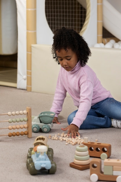 Foto grátis garota de tiro completo brincando com brinquedos ecológicos dentro de casa