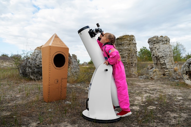 Foto grátis garota de tiro completo com telescópio