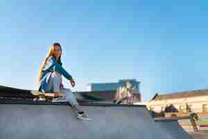 Foto grátis garota de tiro completo sentada no skate park
