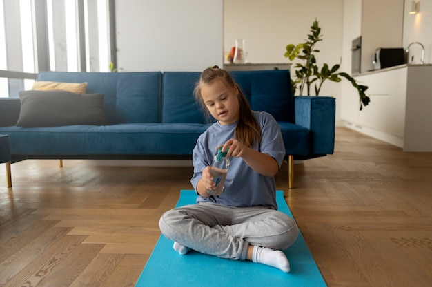 Garota de tiro completo sentada no tapete de ioga