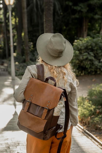 Garota de tiro médio com chapéu andando na natureza