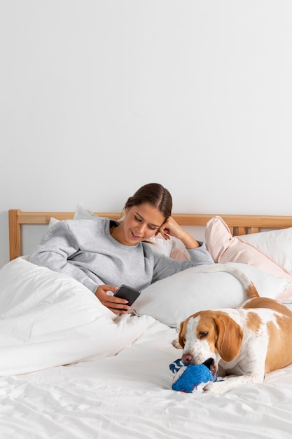 Garota de tiro médio com telefone e cachorro