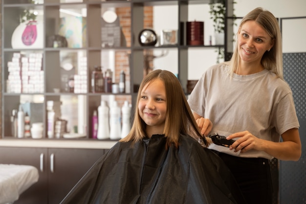 Foto grátis garota de tiro médio cortando o cabelo no salão