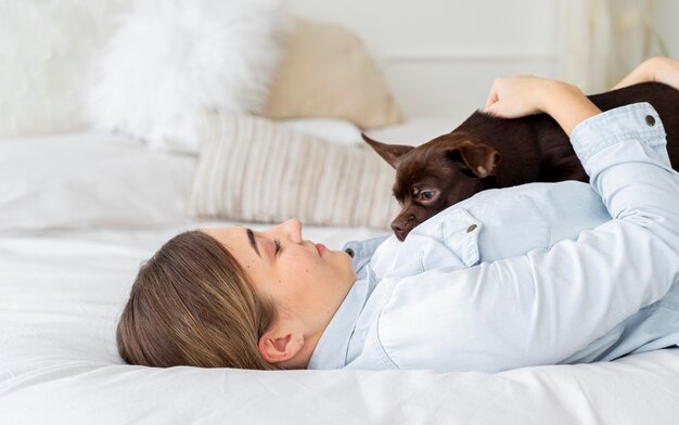 Garota de tiro médio deitada na cama com cachorro