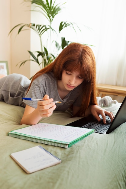 Garota de tiro médio estudando com laptop