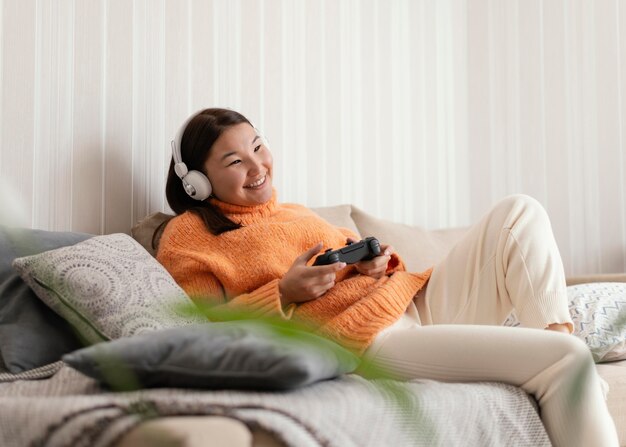 Garota de tiro médio jogando videogame no sofá