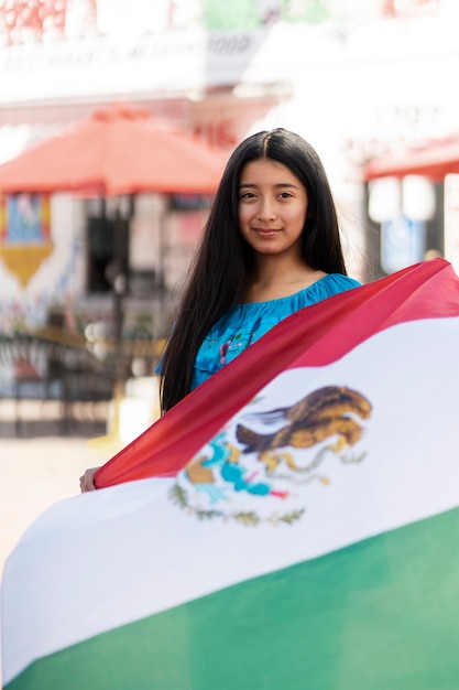 Garota de tiro médio segurando a bandeira mexicana