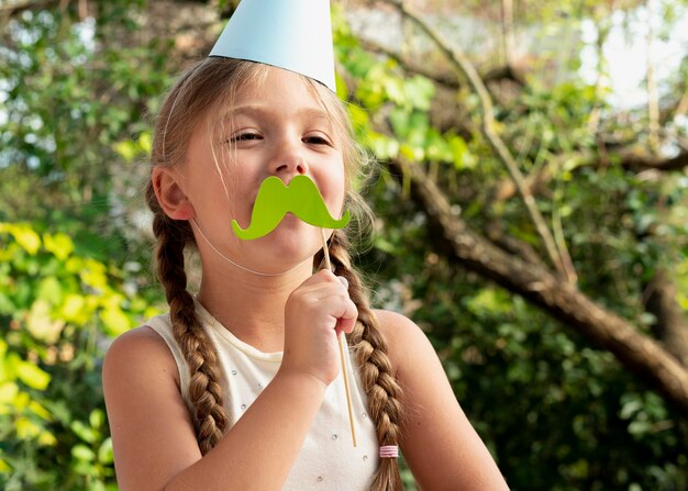 Garota de tiro médio segurando bigode