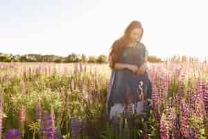 Foto grátis garota de vestido azul andando no campo de flores.