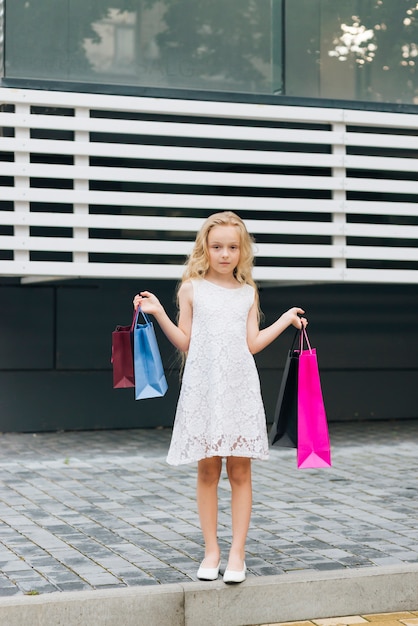 Garota de vista frontal segurando sacolas de compras