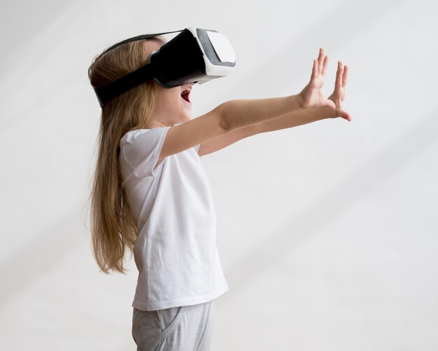 Garota de vista lateral com fone de ouvido de realidade virtual