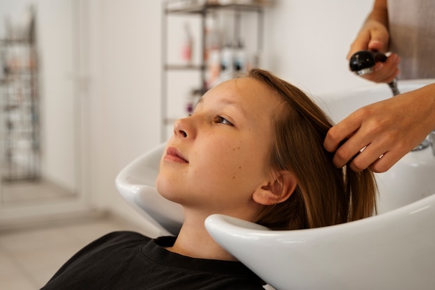 Foto grátis garota de vista lateral lavando o cabelo no salão