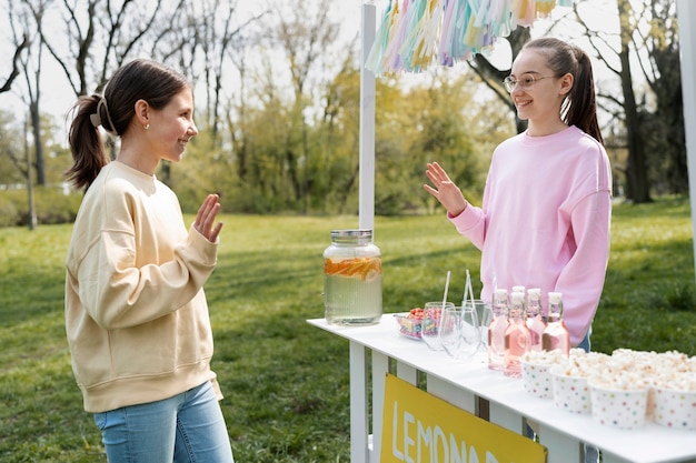 Foto grátis garota de vista lateral vendendo limonada