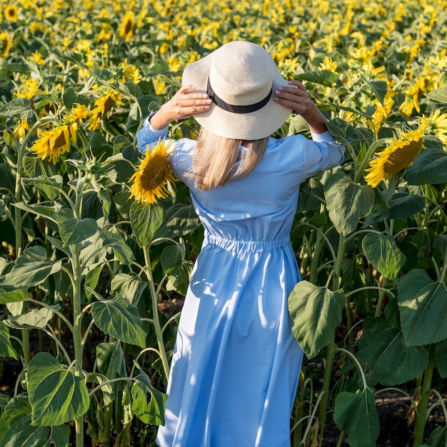 Garota de vista traseira caminhando em um campo com flores do sol