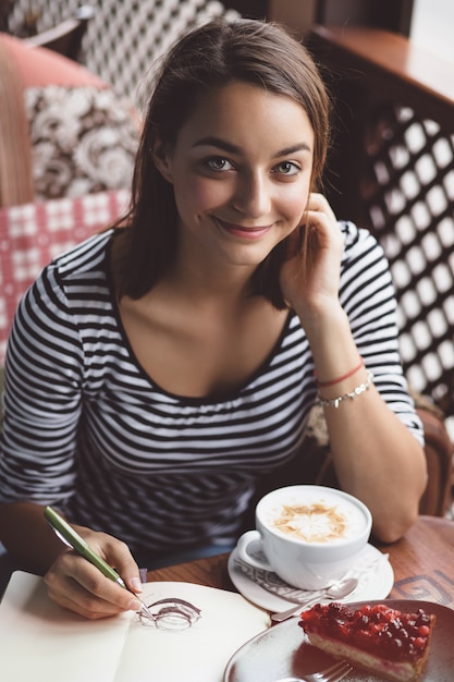 Garota desenhando uma xícara de café no caderno