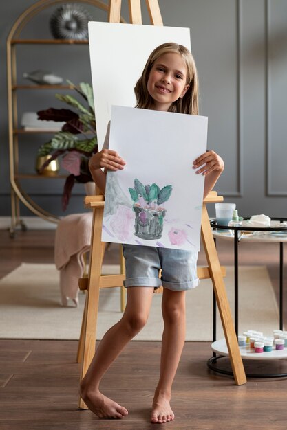 Garota em cena completa segurando uma pintura