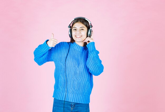 garota em fones de ouvido aparecendo um polegar em rosa.