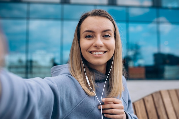 Foto grátis garota em fones de ouvido tomando selfie ao ar livre