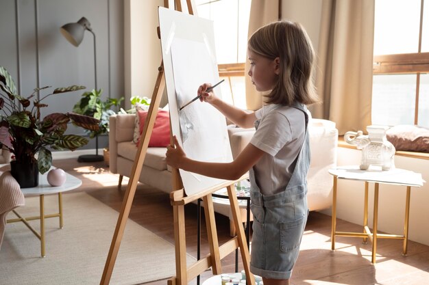 Garota em plano médio pintando em casa