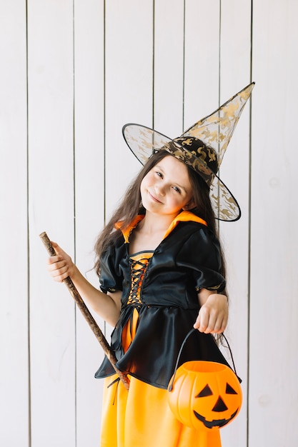 Garota em traje de halloween com cesta de abóbora posando no estúdio