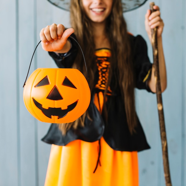 Garota em traje de Halloween segurando a cesta na mão