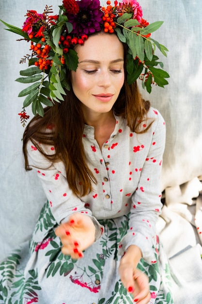 Garota em um vestido de linho. com uma coroa de flores na cabeça.