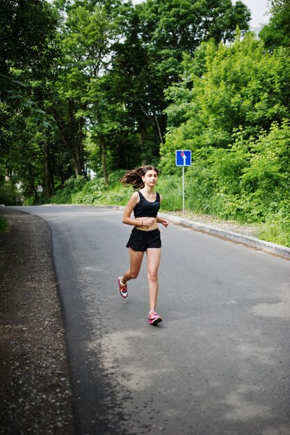 Garota esportiva em roupas esportivas correndo em um parque verde e treinando na natureza Um estilo de vida saudável