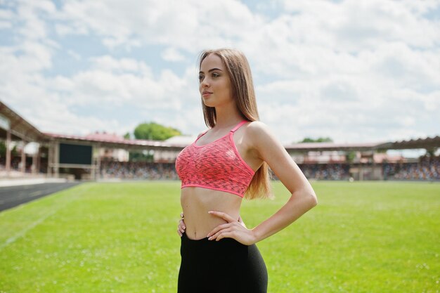 Garota esportiva fitness em roupas esportivas em um estádio de futebol esportes ao ar livre Treino de mulher sexy feliz no fundo da grama verde