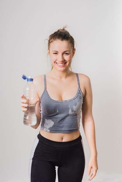 Garota esportiva molhada com garrafa de água