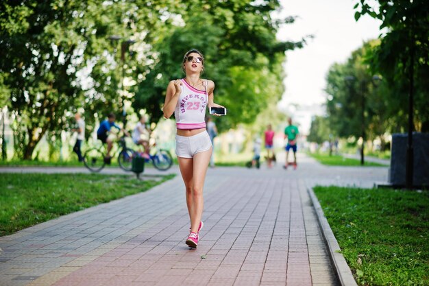 Garota esportiva usa shorts brancos e camisa correndo no parque