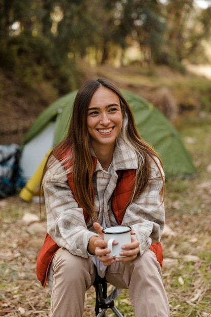 Garota feliz acampando na floresta sorrindo