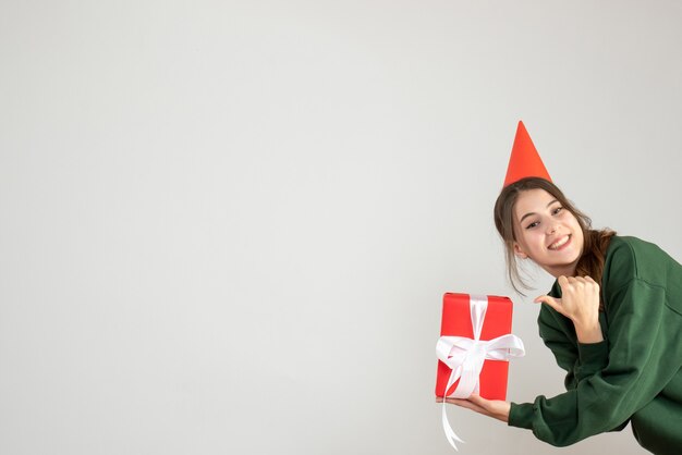 garota feliz com boné de festa fazendo polegar para cima sinal em branco